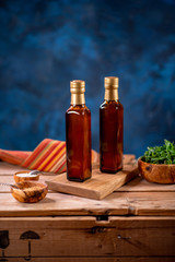 Two bottles of olive oil with bowl of olives and salad on wooden board