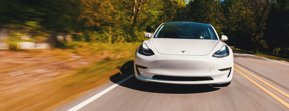 A New Tesla Model 3 All Electric Car Driving Down The Road