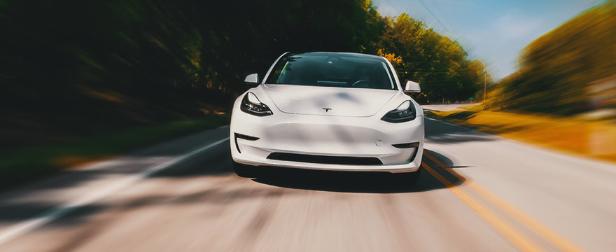 A new Tesla Model 3 all electric car driving down the road