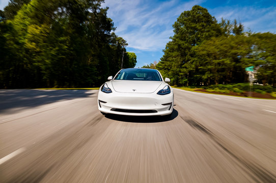 A New Tesla Model 3 All Electric Car Driving Down The Road