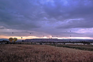 Cappadocia The dawn begins. In the cloudy sky rises many colorful balloons over valleys and gorges. Away the mountains.
