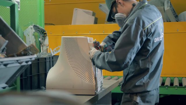 Dumpsite worker is dismantling an old computer monitor