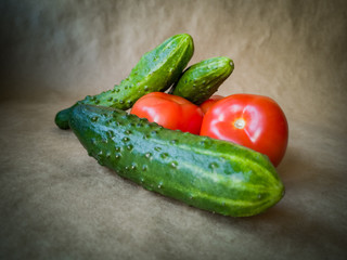 Fresh tomatoes and cucumbers on a dark background. Red tomatoes and green cucumbers close up