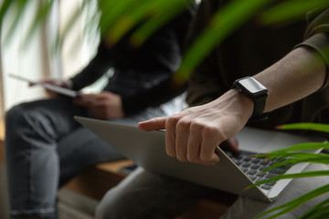 Close up of two people, couple using smartphone, laptop, smartwatch, education and business concept, communication during self-insulation. Surfing, online shopping, working, studying, chatting.