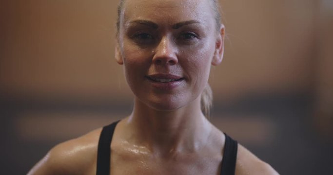 Fit young woman in sportswear sweating and
smiling while standing in a gym after a workout
session
