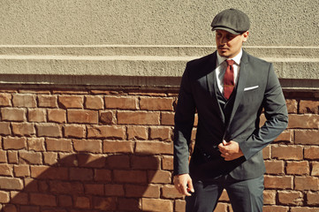 Portrait of retro 1920s english arabian business man wearing dark suit, tie and flat cap.