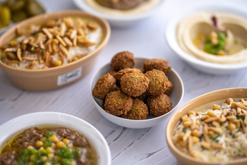 arab breakfast with hummus and falafel and fattah and foul on white wooden table Jordanian food 