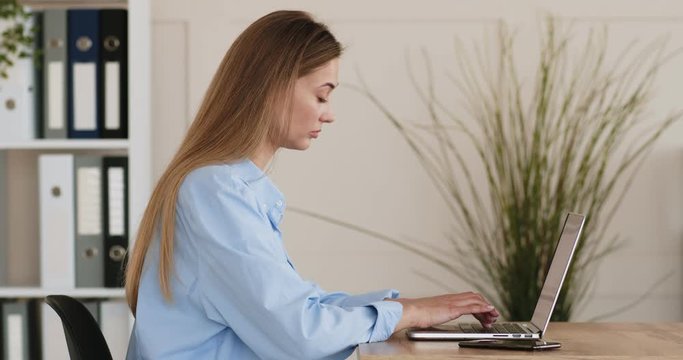 Young woman typing plan on laptop computer, side view