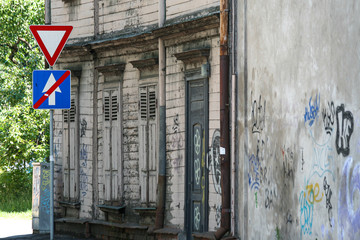 Old timber building with graffiti and a street sign next to it