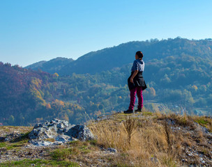 Fototapeta premium Woman standing on top of a hill, staring into the distance towards the mountains