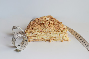a piece of Napoleon’s cake made of puff pastry wrapped in a centimeter tape. lose weight by summer on quarantine