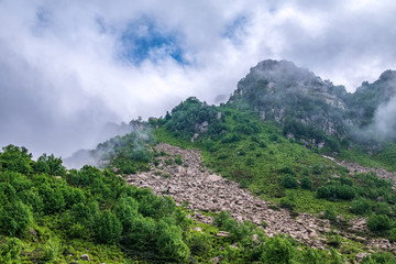 Fototapeta premium Green mountain slope with rocks on cloudy day.