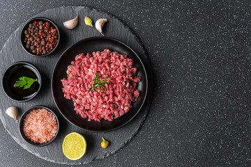 Fresh minced meat ground beef on a black plate against stone background