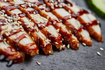 Smoked eel sliced fillet with fresh cucumber, pickled ginger and wasabi on slate plate