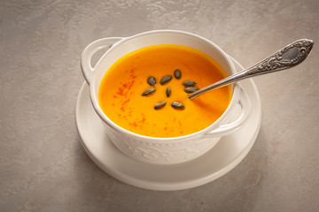 Bowl of tasty pumpkin soup and space for text on gray table, top view