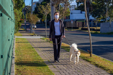 Mulher de máscara passeando com o cachorro