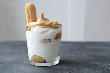 Iced frothy Dalgona Coffee tiramisu, a trendy fluffy creamy whipped coffee on the top of tiramisu dessert. Korean drink latte espresso with coffee foam.