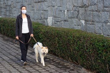 Mulher de máscara passeando com o cachorro
