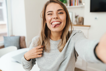Photo of woman sticking out her tongue and winking while taking selfie