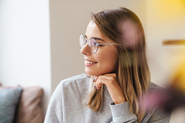 Photo of cheerful young woman in eyeglasses smiling and looking aside
