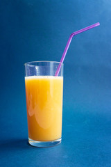 glass of fresh orange juice against blue background with empty space for text, healthy lifestyle concept
