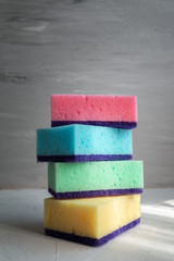 stack of colored sponges for washing dishes against grey background
