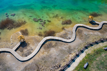 Aerial view of wooden path over turquiose lake colour. Drought. Drone top view.