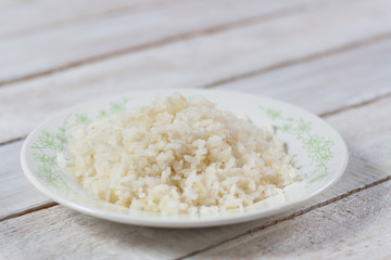 White boiled rice on plate on wooden background