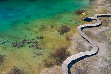 Aerial view of wooden path over turquiose lake colour. Drought. Drone top view.