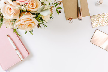 Desktop of blogger with beautiful bouquet of roses and notebook on white desk with copy space. Mood...