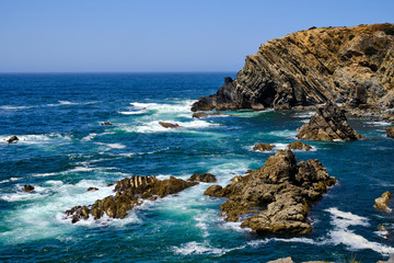 Waves crash on the cliff. Solo Backpacker Trekking on the Rota Vicentina and Fishermen's Trail in Alentejo, Portugal. Walking between cliff, ocean, nature and beach.