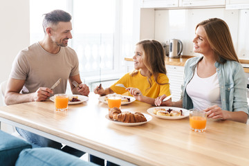 Obraz na płótnie Canvas Photo of happy family smiling and talking while having breakfast