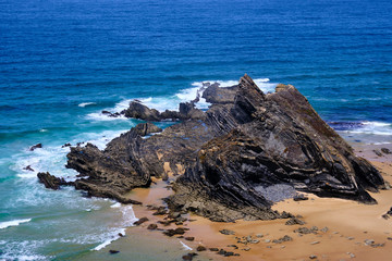 Waves crash on the cliff. Solo Backpacker Trekking on the Rota Vicentina and Fishermen's Trail in Alentejo, Portugal. Walking between cliff, ocean, nature and beach.