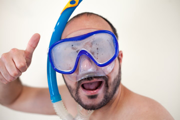 Happy man enjoying vacation with thumb up wearing snorkel goggles and isolated background