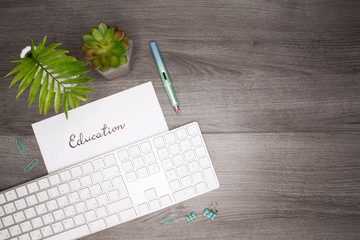 Business flat layout with calligraphic writing "education", palm and plant on gray wooden background