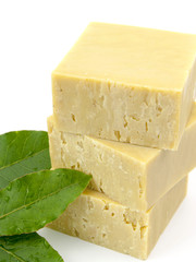 fresh laurel leaves and laurel soap on top of a white background.