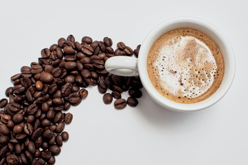 A cup of strong coffee. Brown coffee beans on a white table.