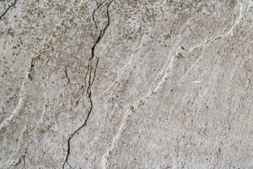 Close up, macro image of textured concrete paving with a crack running from top to bottom of the image.