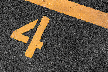 Asphalt parking lot with yellow lot line and yellow lot number 4, four, fourth.