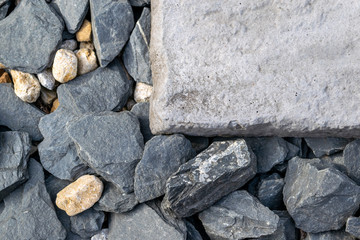 Close up of grey textured aggregate and rocks with a single grey textured block paving stone to the top right hand part of the image.