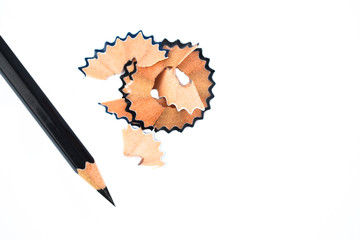 Photograph of some pencil shavings placed beside a black color wood pencil