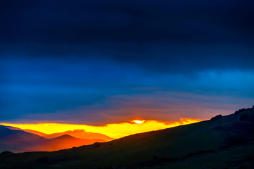 Sun setting over Silhouetted Mountains, Clouds 
