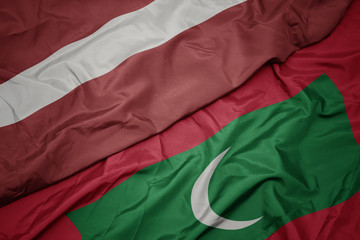 waving colorful flag of maldives and national flag of latvia.