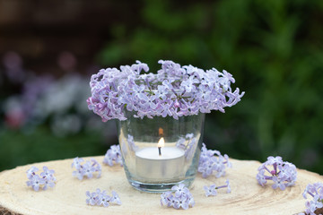 Kerze im Glas mit Fliederblüten geschmückt als Dekoration