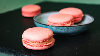 sweets advertising concept, french dessert - pink macaroon on a black background, close-up