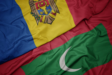 waving colorful flag of maldives and national flag of moldova.