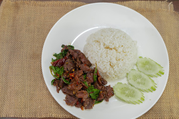 Pad Kra Pao Beef - Stir fried beef with holy basil on Sack cloth above the wooden table - Horizontal