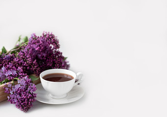 Branches and flowers of lilac, violet color, on a white background. Cup with coffee, cocoa, spring breakfast. Creative flat lay, frame for text. Minimalistic design.  Panoramic banner background with 
