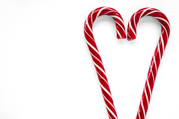 Two red candy canes in the shape of a heart on a white background