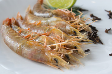 Fresh prawns on a white plate with lemon and dill